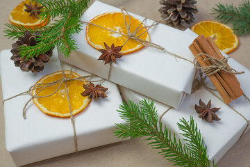 New Year composition. On beige craft paper, gift boxes, dry orange slices, pine cones, cinnamon, cloves. Cozy Christmas concept.