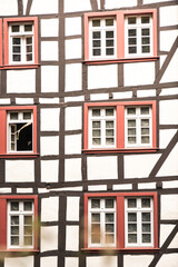 Fototapeta premium Fachwerk, altes Haus in Deutschland, Holz, antiker Holzbau, rote Fenster, Sprossen