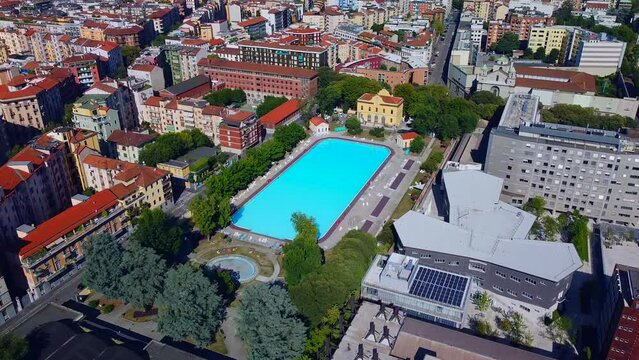 Aerial view of the cityscape and Milano Sport - Centro Balneare Romano swimming pool with clear water. Polytechnic University buildings. Campus and library. Milan Italy 10.2022