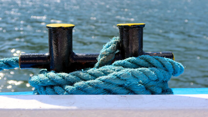 Mooring rope and bollard on sea water background, closeup