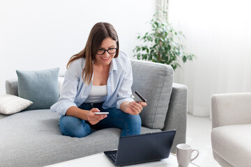 Shopping online at home. Happy woman paying by credit card for delivery order and purchases. Girl buying insurance with laptop and smartphone. Technology lifestyle for young investors, e-commerce