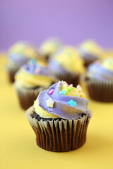 Three yellow and purple easter cupcake on lined background