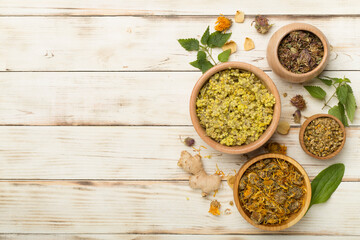 Different herbs in bowls on wooden background, top view