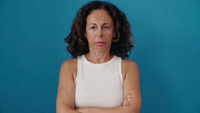 Middle age woman standing with sad expression over isolated blue background