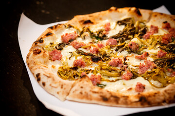 Pizza with friarielli (Neapolitan broccoli) on black background . Pizza recipe and menu.