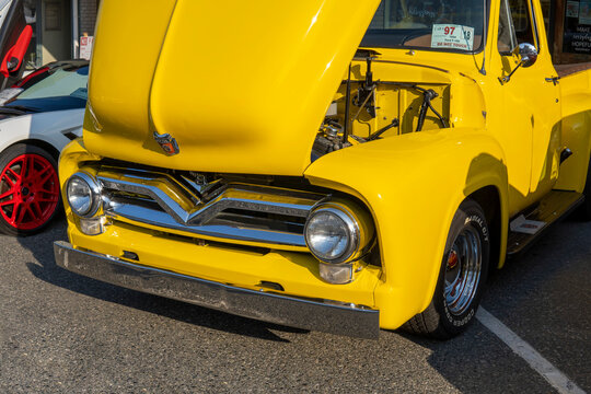 Headlights of yellow Ford F100 Pickup with open car hood. 1954 retro Ford at car exhibition. Snohomish, WA, USA - September 2022