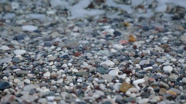 Small sea waves rush onto the shore from small pebbles. Very close-up. Peace from the movement of sea water or waves. High quality FullHD footage