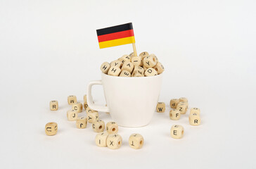 Obraz na płótnie Canvas The flag of Germany sticks out of a cup with cubes on which letters are depicted