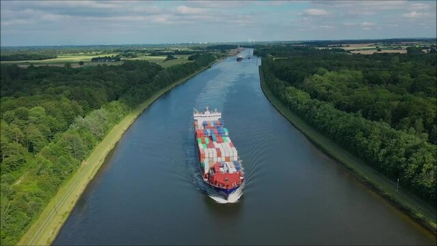 Aerial top down view from the container ship following along Kiel Kanal. The view of container ship from the air. Birdseye view flying low around large cargo ship passing Kiel Kanal.