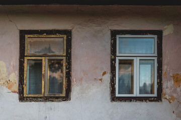 Fototapeta premium Windows of an old cottage, old and new window on concrete wall, broken facade, countryside, Slovakia, Europe