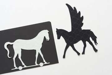 glyphs or dingbats of pegasus (winged horse) and hobby or trojan horse cutouts on blank paper