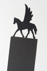 glyph or dingbat of pegasus or winged horse cutout and black paper form