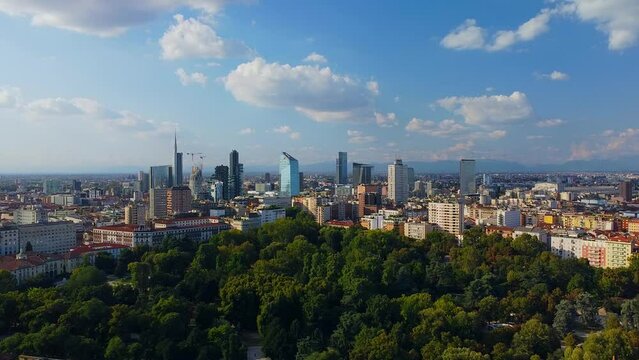 Aerial view of autumn trees in Giardini Indro Montanelli park and the skyline with new skyscrapers. View of modern business offices. Ecology. Clouds over the city. Green Planet. Milan. Italy, 
