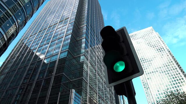 vertical traffic light with blue sky and skyscraper in the background.	