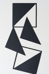 black geometric paper shapes (squares with triangles) on blank paper