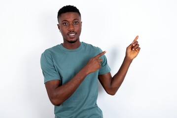young handsome man wearing green T-shirt over white background with positive expression, indicates...