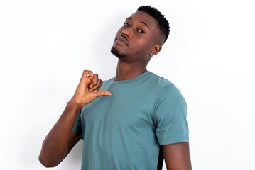 Closeup of cheerful young handsome man wearing green T-shirt over white background looks joyful,...