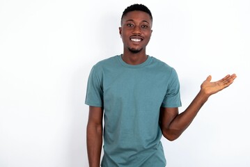 Positive glad young handsome man wearing green T-shirt over white background says: wow how exciting it is, has amazed expression, shows something on blank space with open hand. Advertisement concept.