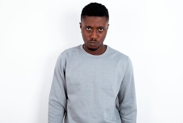 Fototapeta premium Offended dissatisfied young handsome man wearing grey sweater over white background with moody displeased expression at camera being disappointed by something