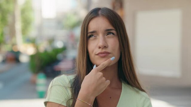 Young beautiful hispanic woman standing with doubt expression at street