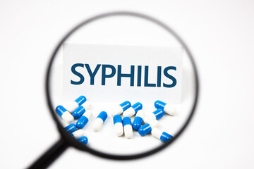Text SYPHILIS on a sheet through a magnifying glass. The concept of syphilis diagnosis.