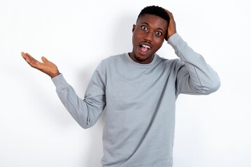 Shocked amazed surprised young handsome man wearing grey sweater over white background hold hand offering proposition