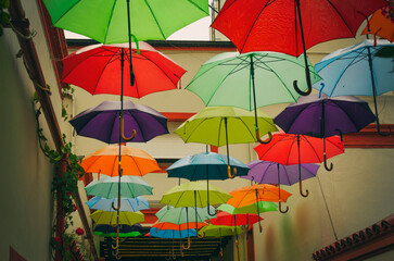 Colorful hanging umbrellas with slightly noticeable water drops 