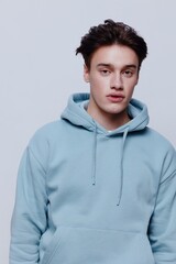 vertical portrait photo .a pleasantly smiling young man in a light light blue hoodie, a place in the background for inserting an advertising layout