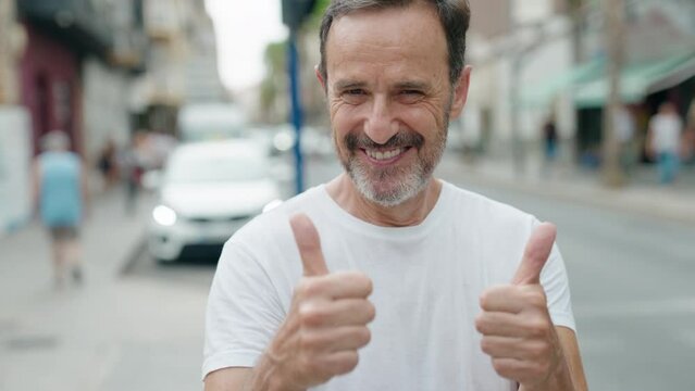 Middle age man smiling confident doing ok sign with thumbs up at street