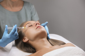 Beautiful woman getting facial injection in salon