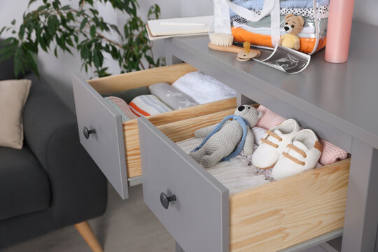 Open drawers of chest with baby stuff in room