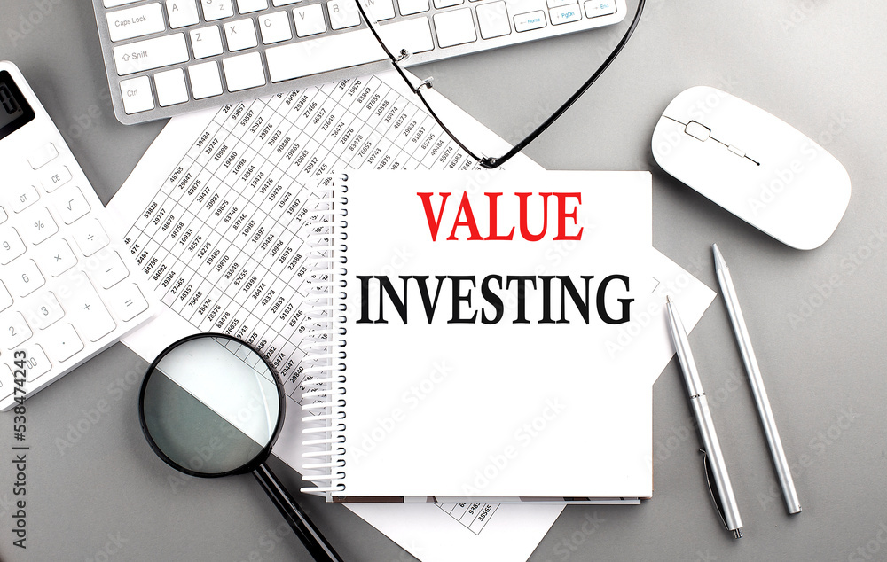 Poster value investing text on notepad on chart with keyboard and calculator on grey background