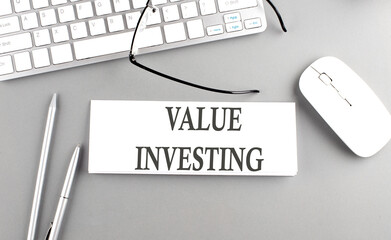VALUE INVESTING text on paper with keyboard on grey background