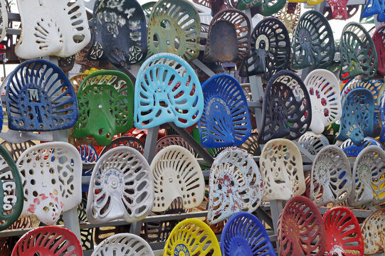 Display of multi-colored, hand-painted vintage metal tractor seats