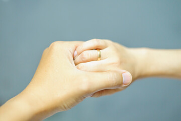 Someone gently holds the hands of the girl isolated with grey background