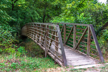 The rusty metallic footbridge connects the forest with the hiking path