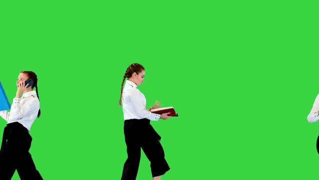 Three nice girls in white shirts walk with folds in hands, dancing slightly on a Green Screen, Chroma Key.