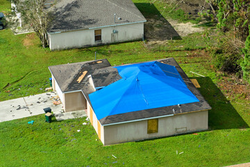 Top view of leaking house roof covered with protective tarp sheets against rain water leaks until...