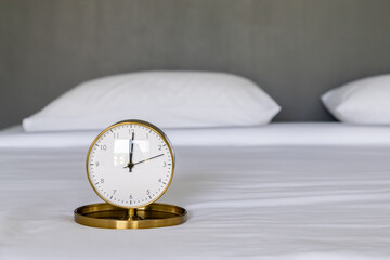 Clock in white bed. Concept of waking up. Time of rest.