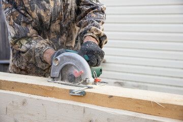 Hands of carpenter work with grinder saw on wooden boards