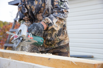 Hands of carpenter work with grinder saw on wooden boards