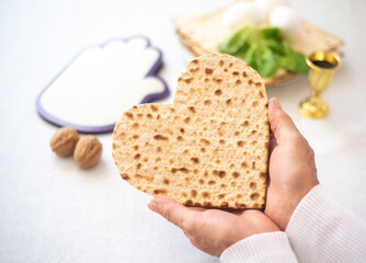 Woman's hands holds Matzah shape of heart. Traditional of Jewish Holiday on Passover. Home symbol of lovely family. top view, layout. love and care. Gift for lovers. Feeling in love and blissful life