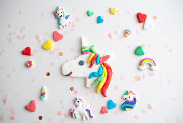 Handmade from color dough shape of unicorn, rainbow, colorful hearts and confetti for decorate cake on white background. Birthday party for child