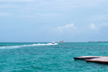 A picture of a speed boat moving towards a cruise boat in the blue sea