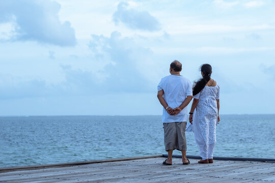 A picture of two couples standing in the edge of a platform and looking at the beautiful blue sea and sky
