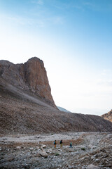 three tourists with backpacks in the mountains. Tourists travel through the rocky mountains. Active rest in mountain hiking. Adventure in the mountains.