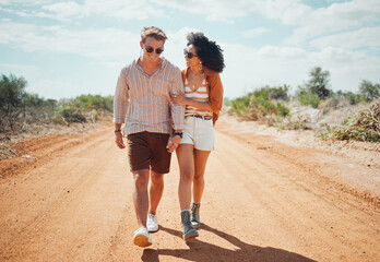 Couple, sunglasses and walking on dirt road in nature on holiday, vacation or summer safari trip. Diversity, love and man, woman and travel outdoors, talking and bonding or spending time together. © K Abrahams/peopleimages.com
