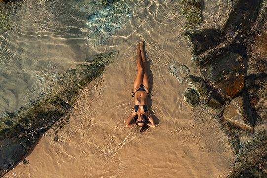Top Aerial View of Tanned Woman in Bikini on the Rocky Beach on Summer