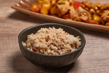 cooked brown rice in a cup on wooden background