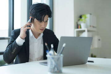 Attractive businessman working on laptop in workstation office.